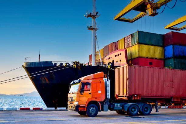 Camion porte-conteneurs à quai devant un navire de fret